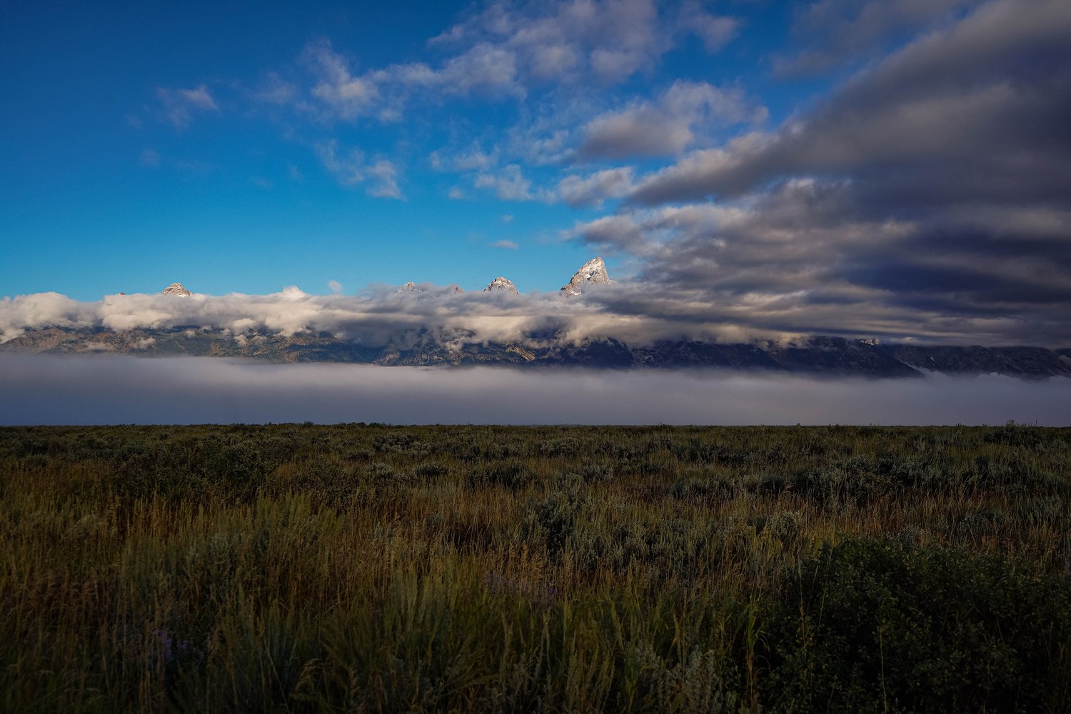 The Teton Range half hidden in cloud above the sagebrush flats.